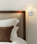 Phoebe 8 Inch Modern Wall Sconce With Frosted Seeded Glass Cylinder Shade In Chrome Finish above bed in stylish bedroom