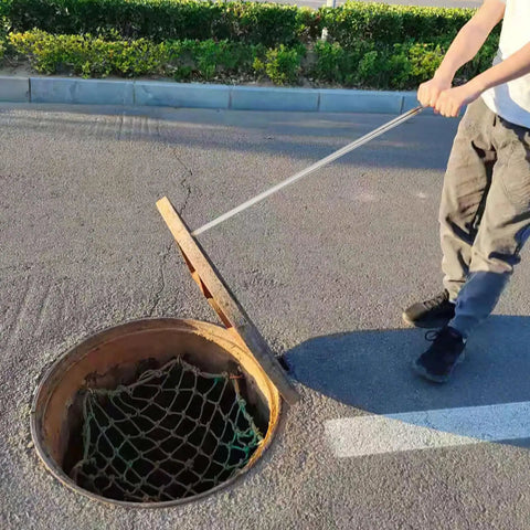 Man using No Sweat Heavy Duty Manhole Cover Lift Hook With T Shaped Steel Puller For Drain Well Lid Opener to open drain lid.