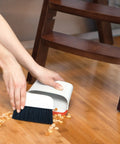 Compact Dustpan And Brush Set With Snap In Design And Bristle Cover used on hardwood floor under chair