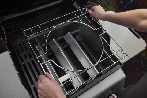 Hands adjusting the grill grates on a Propane Grill For Outdoor Cooking And BBQ With 2 Burners Black Finish Porcelain-Enameled Cast Iron Grates