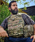 Man in tactical gear with IFAK Trauma Kit With CAT Tourniquet And Israeli Bandage Wound Care Essentials in MOLLE pouch outdoors.