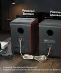 Rear view of powered and passive Bluetooth bookshelf speakers, showing cable connections and outlets on wooden table.