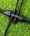 Black connector with tubes on grass, part of 22 Pack 1/4 Inch Drip Irrigation End Cap Connectors End Plug Fittings For 1/4 Inch Tubing.