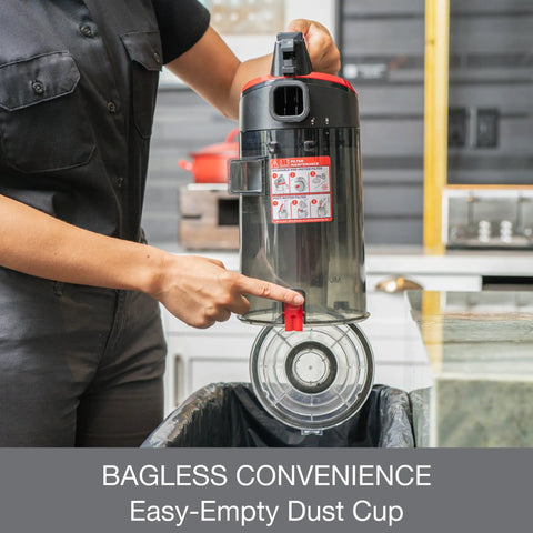 Commercial Grade Upright Vacuum Featuring Adaptive Surface Sensing Automation dust cup being emptied into trash.