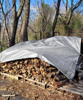 Heavy Duty Tough As Nails Waterproof Tarp 10x12 Ft covering firewood pile in forest with grommets and reinforced edges