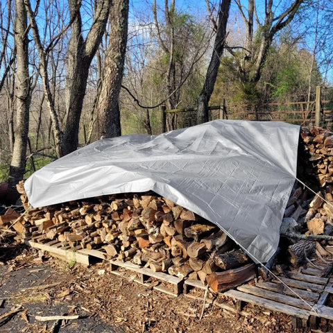 Heavy Duty Tough As Nails Waterproof Tarp 10x12 Ft covering firewood pile in forest with grommets and reinforced edges