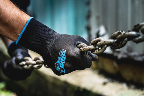Close-up of Never Slip Maximum Grip All Purpose Work Gloves For Men With Polymer Palm gripping a chain outdoors.