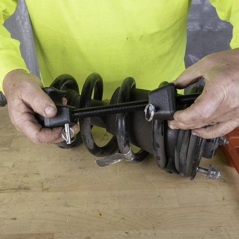 Hands using MacPherson Strut Coil Spring Compressor Tool For Safe And Easy Spring Compression Pro Grade Durable Construction
