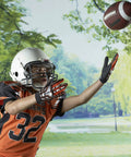 Junior Youth Football For Kids With Extra Grippy Synthetic Leather Ball being caught by a child in a park, wearing a helmet and gloves.
