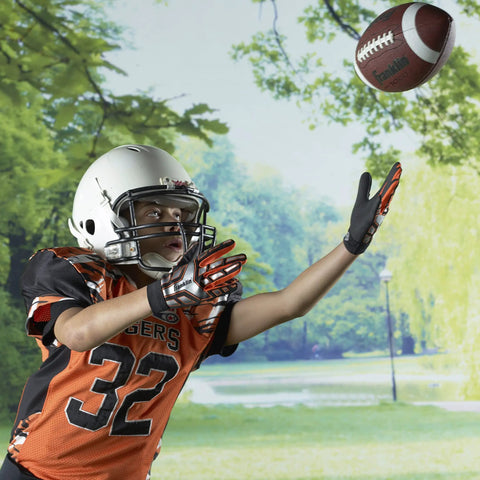 Junior Youth Football For Kids With Extra Grippy Synthetic Leather Ball being caught by a child in a park, wearing a helmet and gloves.