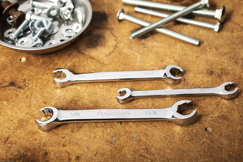 Three Piece SAE Flare Nut Wrench Set Pro Grade Heavy Duty Tools For Soft Metal Nuts laid on a workshop table with bolts nearby.