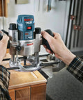 Person using Bosch router tool on wood surface in workshop setting