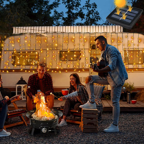 Evening scene with people enjoying a campfire and Solar Curtain Lights Outdoor 200 LED Set, 13Ft by 3.3Ft on a camper.