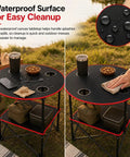 Lightweight Folding Camping Table With 4 Cup Holders Waterproof Canvas Outdoor Table For Beach Camping Tailgating Picnics Campfires Easy Carry Bag Grab And Go Ready For Any Outdoor Session, showing waterproof surface and cleanup.