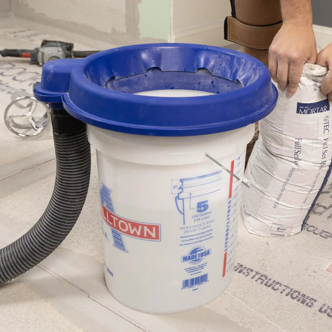 5 Gallon Bucket Dust Collector With High Powered Cyclone Separator And 2 Inch Vacuum Hose Fitting For Serious Jobsite Cleanup with a blue lid and vacuum hose.