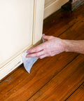 Person using Heavy Duty Cleaning Wipes For Every Surface And Hands, 90 Count on a cabinet baseboard indoors, removing grime.