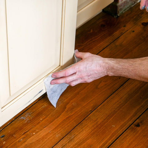 Person using Heavy Duty Cleaning Wipes For Every Surface And Hands, 90 Count on a cabinet baseboard indoors, removing grime.