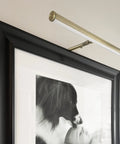 14 Inch LED Picture Light With Integrated LED, 3000K Warm White, 200 Lumens, On Off Switch, Adjustable Decor Wall Light For Indoor Art Displays, Antique Brass Finish mounted on a black frame