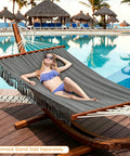 Woman relaxing on Cotton Double Hammock With 55 Inch Spreader Bar by a pool, Dark Gray