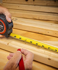 Person using 1-3/16 Inch By 25 Foot Command Control Series Yellow Clad Tape Measure With Anti-Pinch Retractable Tape
