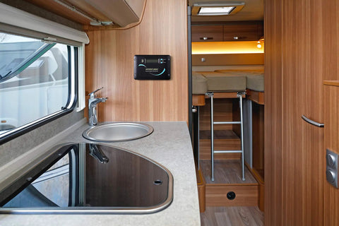 Interior view of a camper van kitchen with sink, stove, and PWM controller, designed for efficient trail camping use.