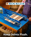 Woodworker using Deluxe Panel Clamps With Scissor Couplers for flat panels and flush joints on a tabletop, precise alignment.