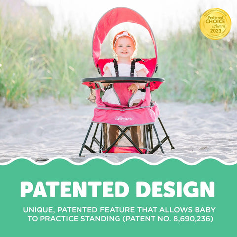 Baby sitting in Go With Me Venture Portable Toddler Chair With Sun Canopy, pink, in sandy outdoor setting, showing patented design.
