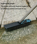 Heavy Duty Push Broom Brush With Tough Stainless Steel Bristles And Solid Handle For Patio Driveway Concrete Deck And Tile Floors Hard As Nails Cleaner at 50-degree angle on a tiled surface.