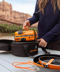 Person packing Genesis Basecamp Camping And Overlanding Stove Cooking System With Included Cookware Orange Portable Dual Burner Camp Stove For Group Meals With Adjustable Flame Control JetLink Compatible