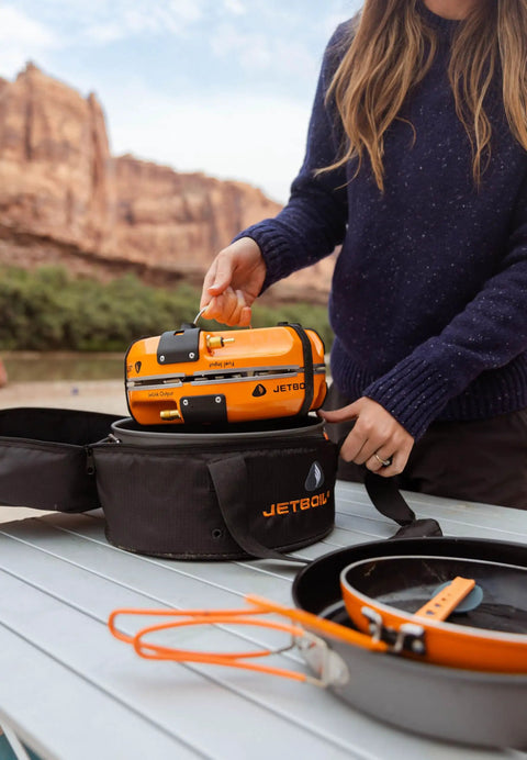 Person packing Genesis Basecamp Camping And Overlanding Stove Cooking System With Included Cookware Orange Portable Dual Burner Camp Stove For Group Meals With Adjustable Flame Control JetLink Compatible