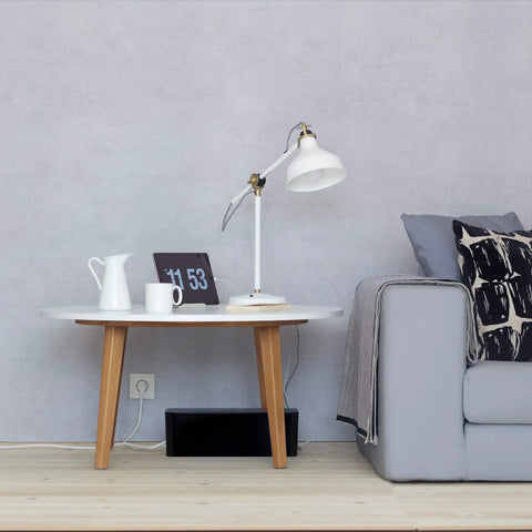 Living room setup showing Desk And TV Cable Box For Cord Management Hide Cables Under Desk Or Beside Your TV Durable High Density Flame Retardant Plastic Fits Wide Surge Protectors With Extra Slack And Adapters Black under a round table.