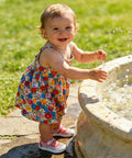 Toddler wearing Kids Water Shoes Quick Dry Aqua Socks For Toddlers And Baby Boys Girls Breathable Quick Dry Upper With Drainage Holes Non Slip Sole Beach Sandals Pink Size 9 9.5 standing by a fountain in a floral dress.