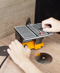 Person adjusting 4 Inch 60W Mini Electric Table Saw For Bench Top DIY Projects Includes Two Circular Blades Handy Compact Hobby Craft Power Tool