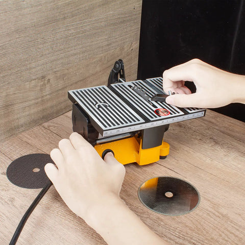 Person adjusting 4 Inch 60W Mini Electric Table Saw For Bench Top DIY Projects Includes Two Circular Blades Handy Compact Hobby Craft Power Tool