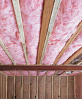 Premium Pink Fiberglass Insulation Batts For Interior Walls And Attic Cavities installed under wooden beams in a ceiling.