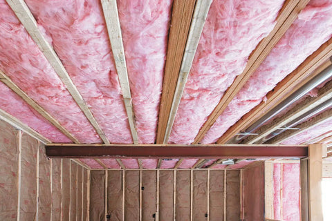 Premium Pink Fiberglass Insulation Batts For Interior Walls And Attic Cavities installed under wooden beams in a ceiling.