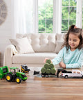 Child playing with 1:32 Scale Farm Toy Set With Tractor, Round Bale Haying Gear And Skid Steer, indoors on table.