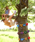 Children climbing a tree using 18 Piece Tree Climbing Holds Set With Six Ten Foot Ratchet Straps For Outdoor Tree Climbing Kit.