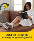 Woman relaxing on sofa wearing cozy self-heating tired and achy feet soothing foot mask with warming booties.