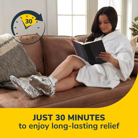 Woman relaxing on sofa wearing cozy self-heating tired and achy feet soothing foot mask with warming booties.