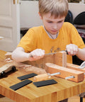 Child using tools with Derby Car Pinewood Weights Kit With 3 Oz Stick On Flexible Weights And Half Ounce Graphite Lubricant nearby