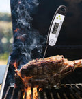 Digital Meat Thermometer For Grilling With Backlit Display, Instant Read In 2 To 4 Seconds, inserted in steak on grill.