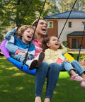 Family enjoying 700 Lb 40 Inch Rainbow Saucer Tree Swing For Kids And Adults Outdoor With Textilene Fabric Weatherproof Heavy Duty Seat UV Resistant Includes 2 Tree Straps in backyard