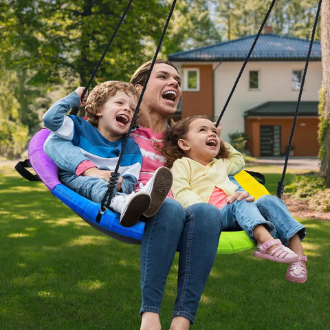 Family enjoying 700 Lb 40 Inch Rainbow Saucer Tree Swing For Kids And Adults Outdoor With Textilene Fabric Weatherproof Heavy Duty Seat UV Resistant Includes 2 Tree Straps in backyard