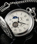 Vintage Mechanical Pocket Watch With Double Sided Floral Engraving Case Hunter Skeleton Design on display on black background.