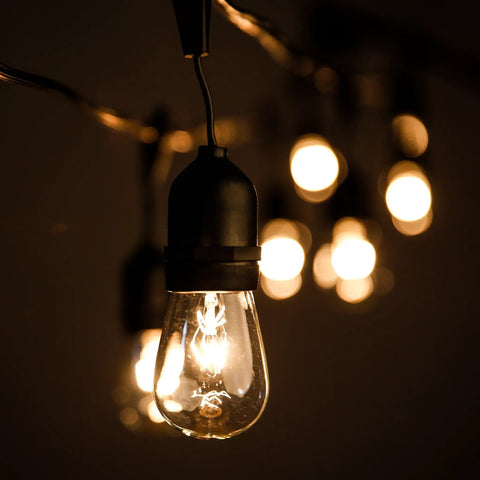 Close-up of illuminated bulb from Beefed-Up 100 Foot Outdoor Commercial String Lights with E26 Suspended Sockets, weatherproof vintage lighting.