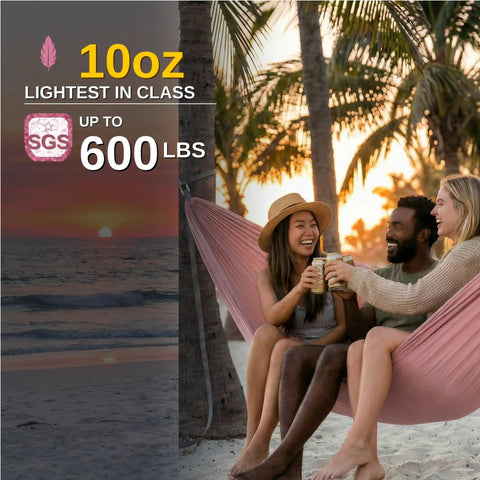 Ultralight Camping Hammock With 600 Lb SGS Certified Capacity in use, beach setting, three people enjoying sunset, pink nylon