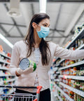 Woman shopping wearing disposable 3 ply face masks pack of 50 breathable ear loop masks in blue for all day comfort