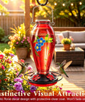 Heavy Duty 24 Oz Hummingbird Feeder For Outdoors Hangin With Thick Glass And Floral Decals, Leak Resistant Metal Base, Five Feeding Ports And Perch, Decorative Red Garden Accent hanging in a garden with hummingbirds feeding.