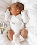 Newborn in white outfit with Wooden Hot Air Balloon Monthly Milestone Cards For Babies, My First Year Sign beside him.
